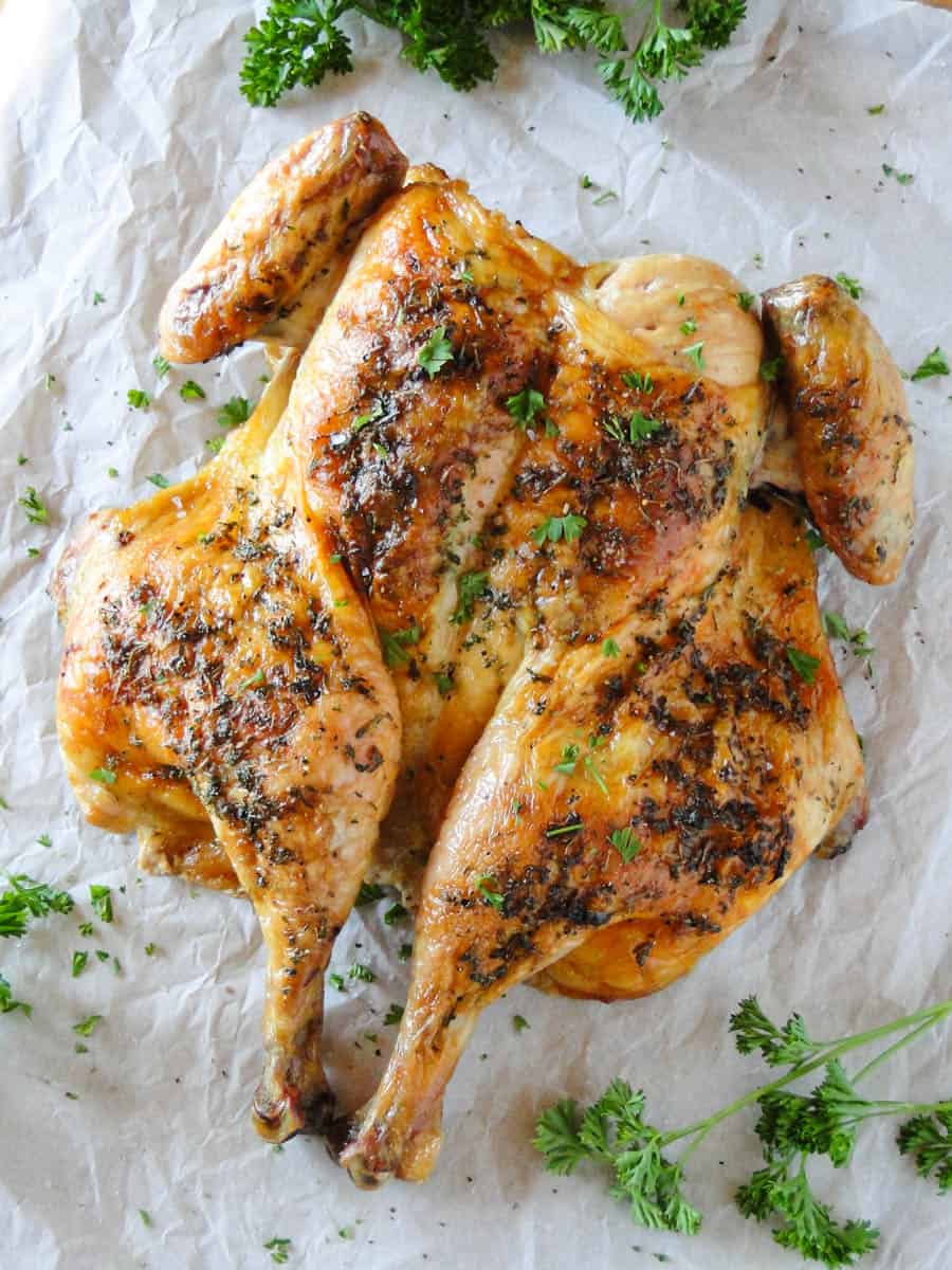 Herb roasted spatchcock chicken garnished with chopped fresh parsley.
