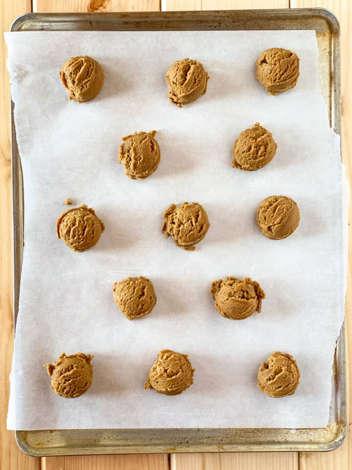 Cookie dough scoops on parchment lined cookie sheet.