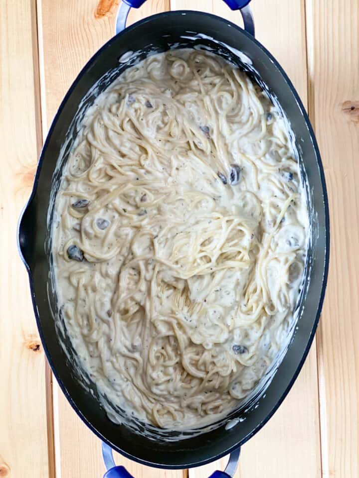 Sauce combined with cooked spaghetti large oval pot.