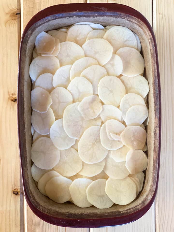 Sliced potatoes layered in casserole dish.