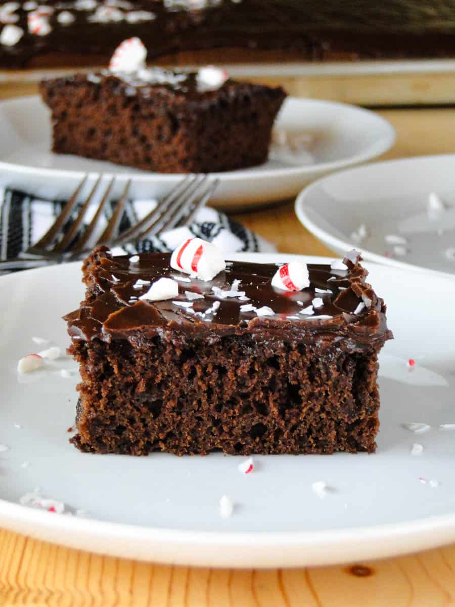 Close up side view of chocolate peppermint sheet cake slices on white round plates.