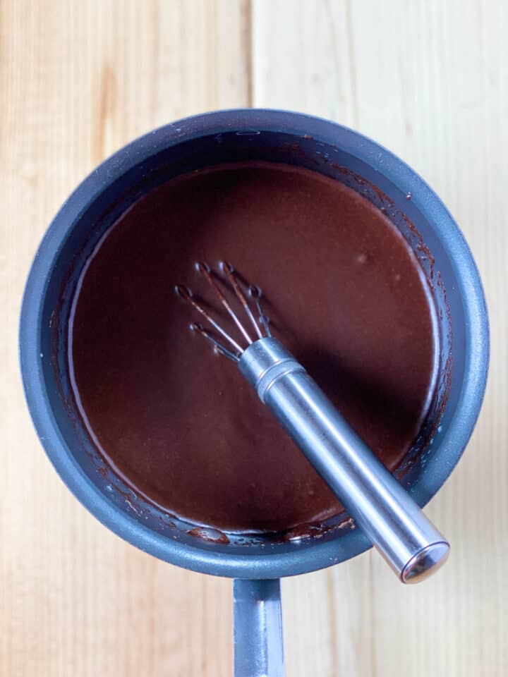 Butter and cocoa powder melted together with water in sauce pot with whisk.