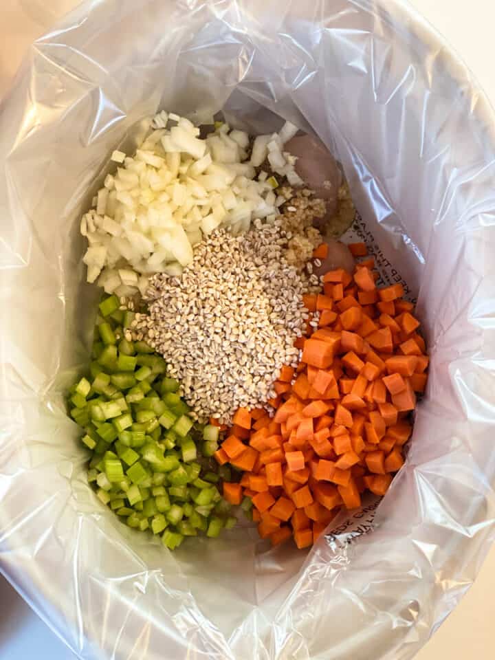 Veggies and barley add on top of chicken in crock pot.