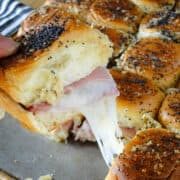 Easy ham and cheese sliders on sheet pan with one slider being pulled out.