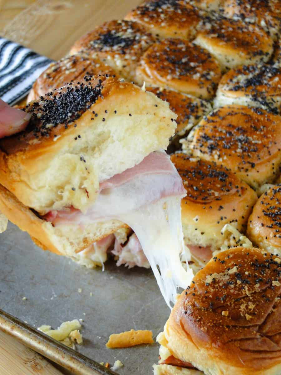 Easy ham and cheese sliders on sheet pan with one slider being pulled out.