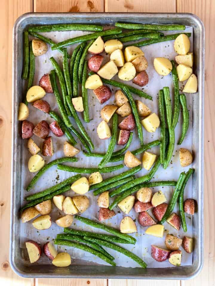 Potatoes and green beans dressed and on sheet pan in single layer.