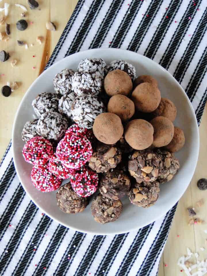 Top view of dark chocolate truffles piled high on white round plate.