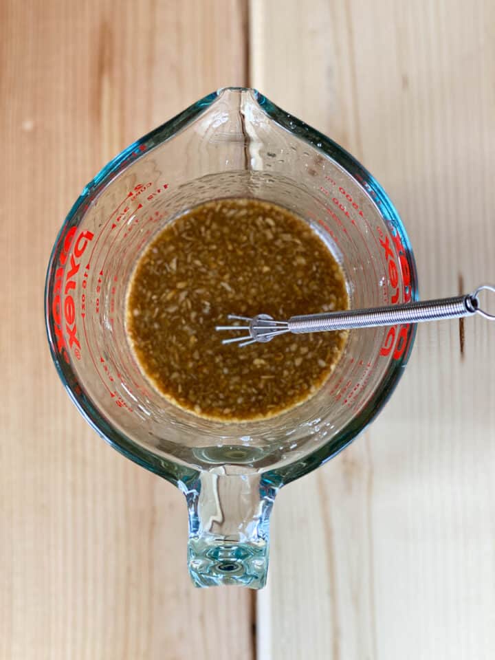 Stir fry sauce with mini whisk in glass measuring cup.