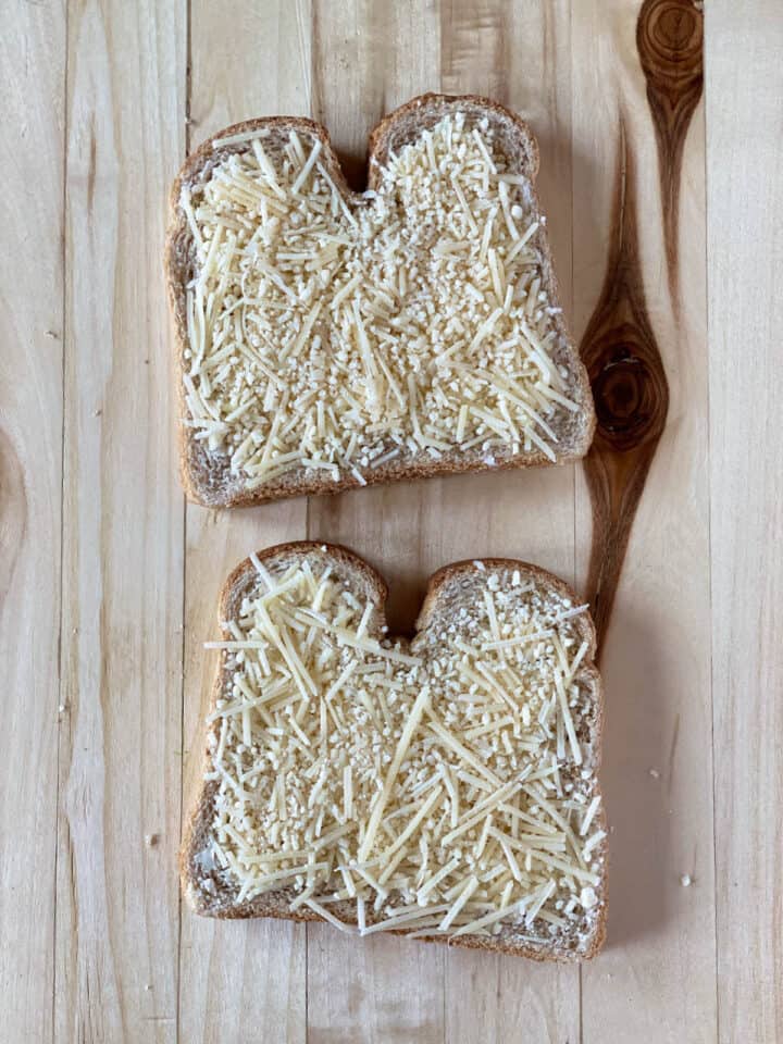 Shredded parmesan on top of garlic buttered bread slices.