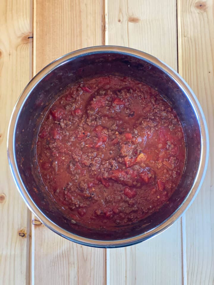 Diced tomatoes and crushed tomatoes added to seasoned cooked beef in instant pot.