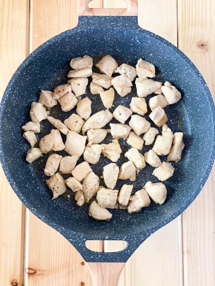 Cubed chicken breast in large round skillet.