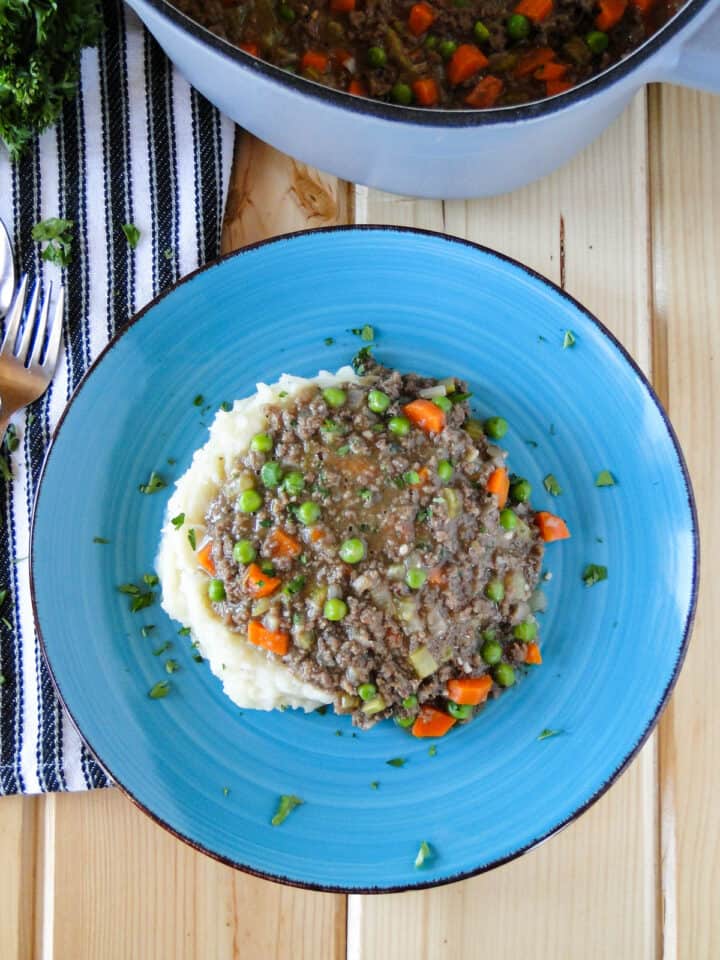 Top view of Irish ground beef stew on round blue plate.