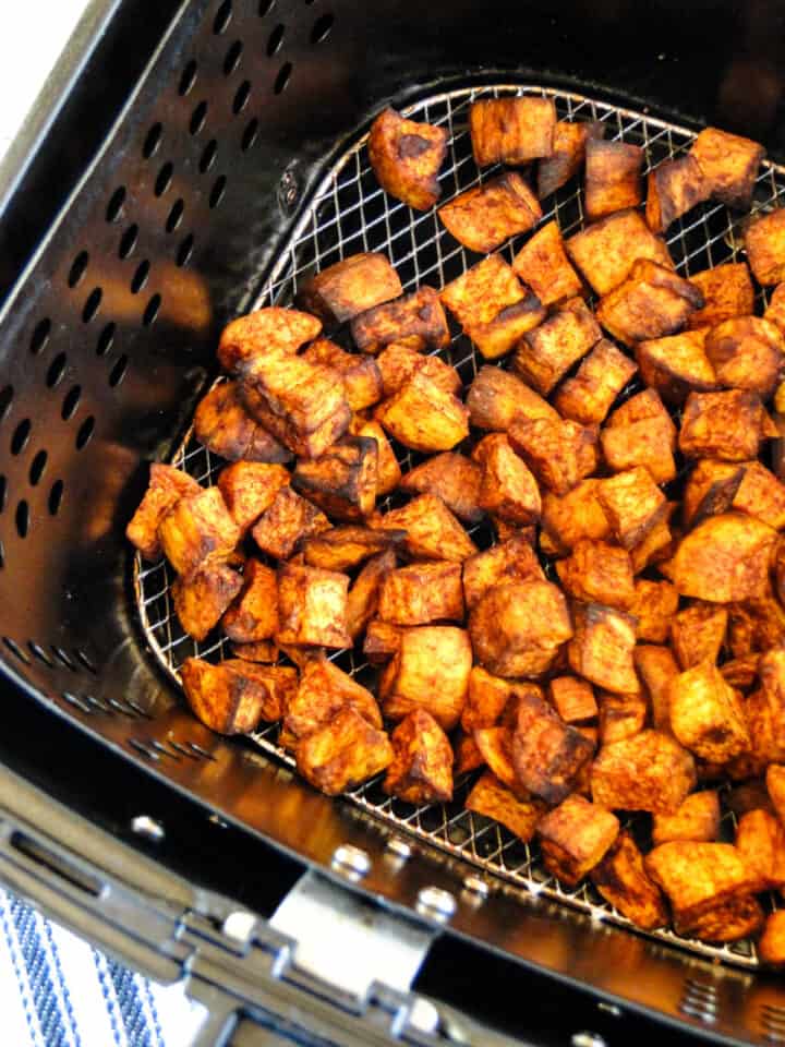 Air fryer cinnamon sweet potatoes in air fryer basket.