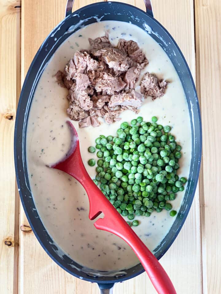 Drained tuna and frozen peas to a large oval skillet.