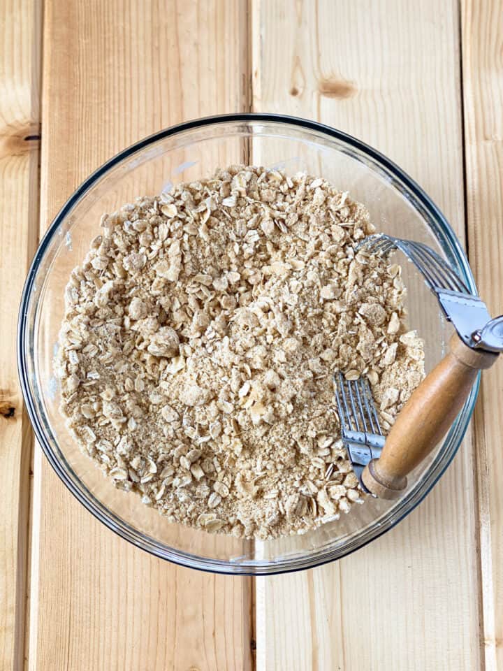 Crisp topping ingredients combined in large glass mixing bowl with pastry blender.