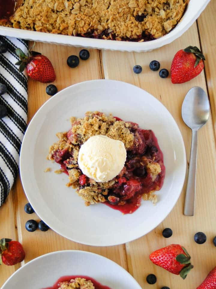 Top view of triple berry crisp served on white round plate topped with a scoop of ice cream.