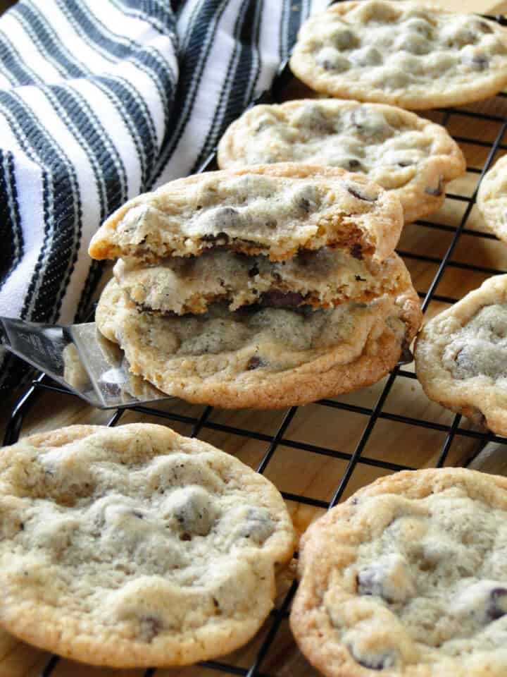 Classic chocolate chip cookies on wire rack with one cookie broken in half.