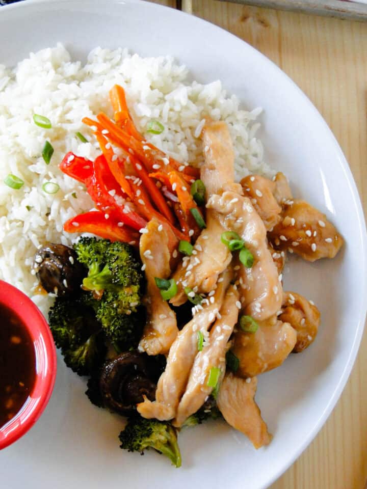 Close up of Easy Sheet Pan Teriyaki Chicken over rice on white round plate.