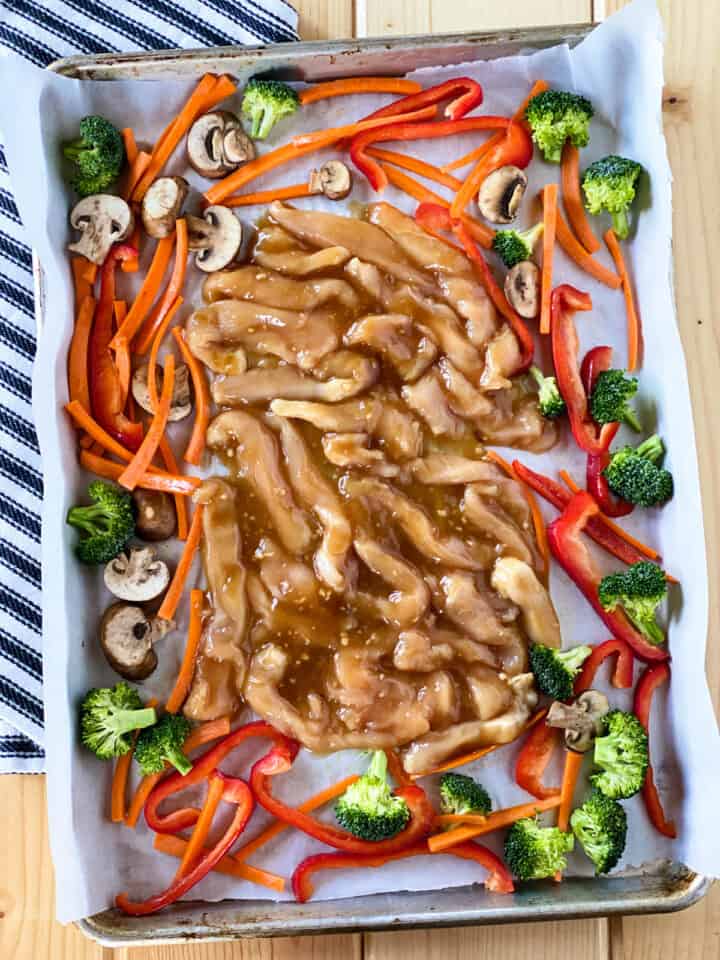 Chicken with teriyaki sauce added to center of sheet pan with veggies.