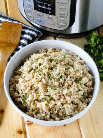 Instant Pot Brown Rice in white round bowl in front of the instant pot.