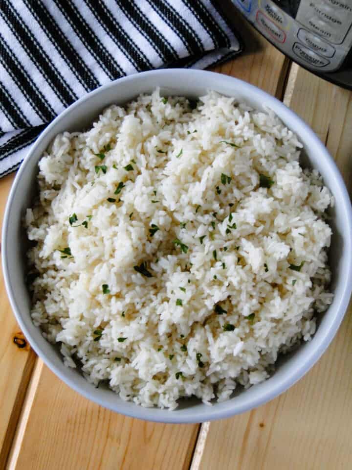Instant pot white rice in white round bowl in front of instant pot.
