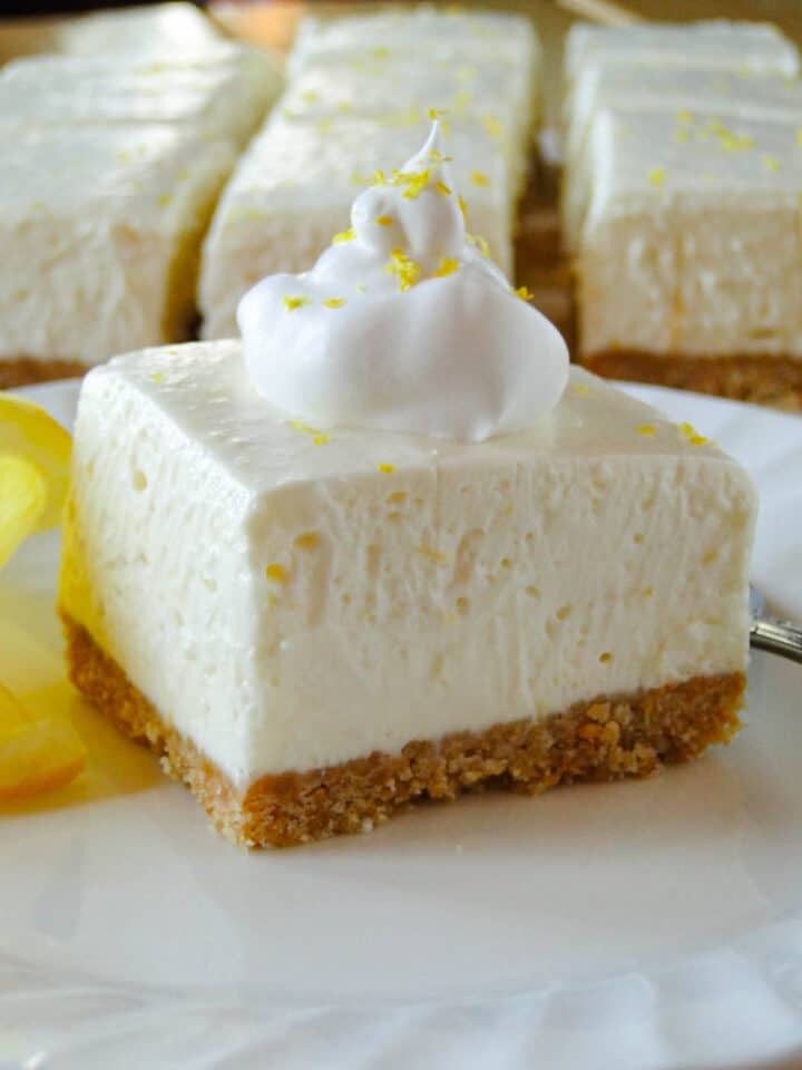 Close up side view of no bake lemon cheesecake bar topped with whipped cream.