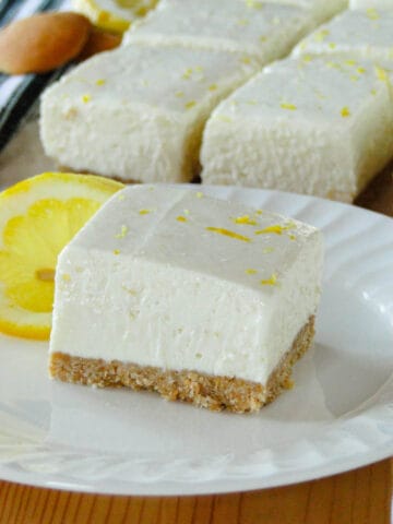 Close up side view of no bake lemon cheesecake bar on white round plate.