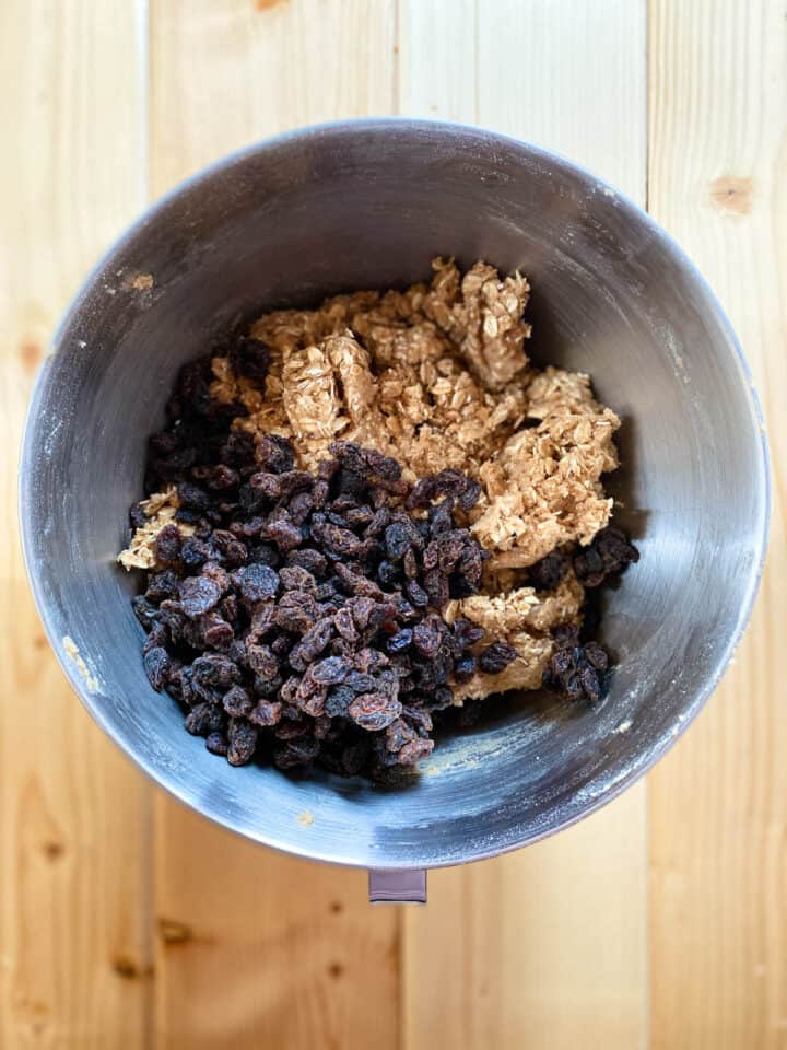 Raisins on top of cookie dough in large mixing bowl.