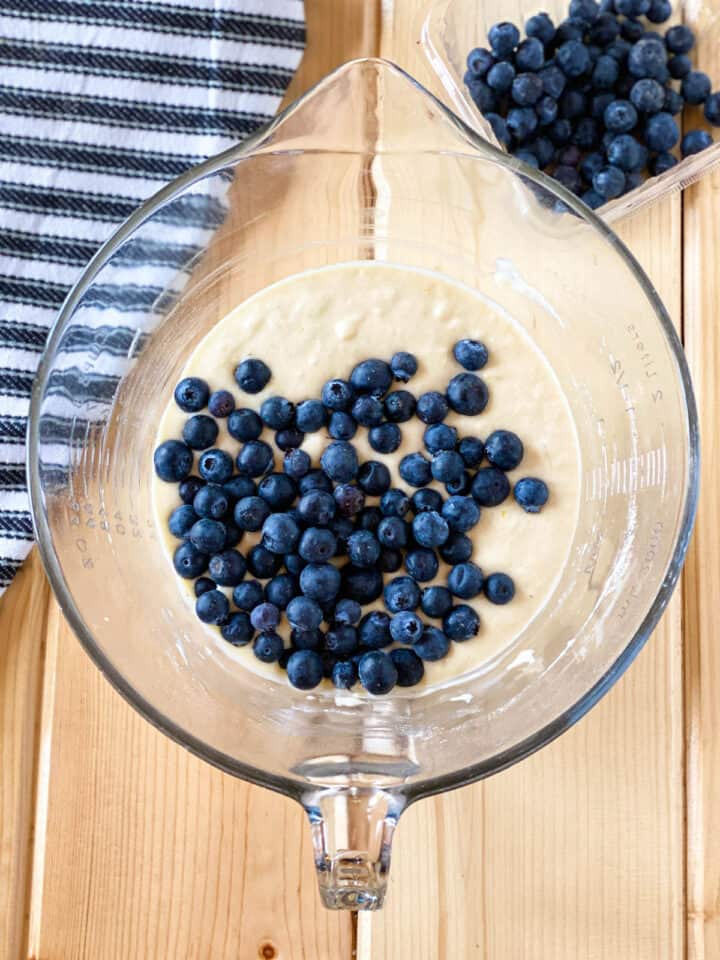 Pancake batter with blueberries on top in large glass mixing bowl.