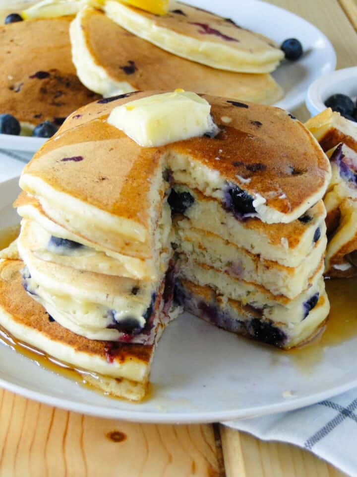 Close up view of blueberry lemon ricotta pancakes with bite cut out showing fluffy inside.