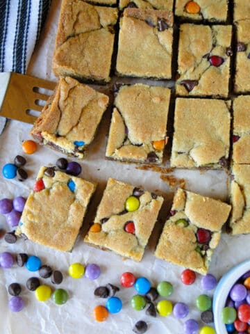 Top view of chocolate chip cookie bars with spatula and extra candies.