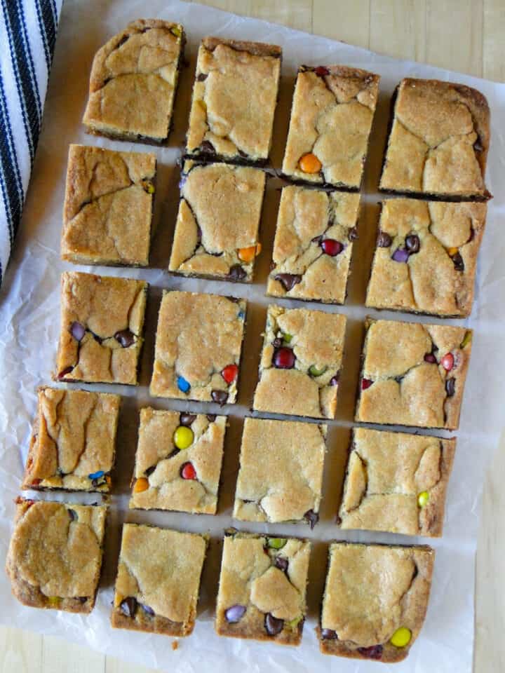 Top view of chocolate chip cookies bars on parchment paper on board.