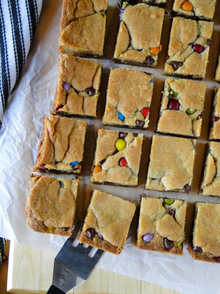 Chocolate chip cookies bars in rows on board with mini spatula.