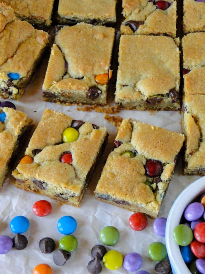 Slices of chocolate chip cookie bars with candies around them.