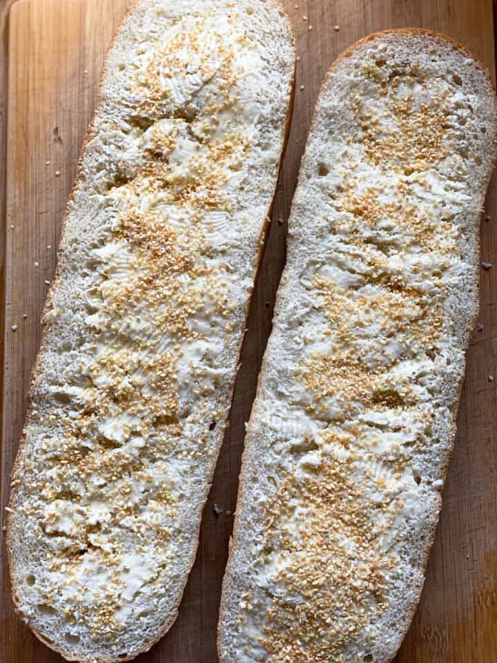 Butter and garlic on french bread loaf halves.