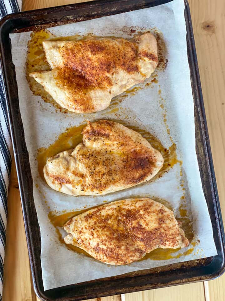 Roasted seasoned chicken breasts on sheet pan.