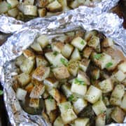 Grilled potatoes in foil packets opened and on sheet pan with serving spoon.