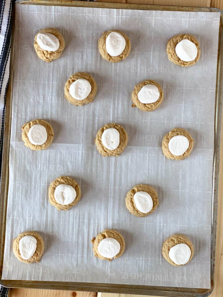 Marshmallows added to graham cracker cookie on cookie sheet.