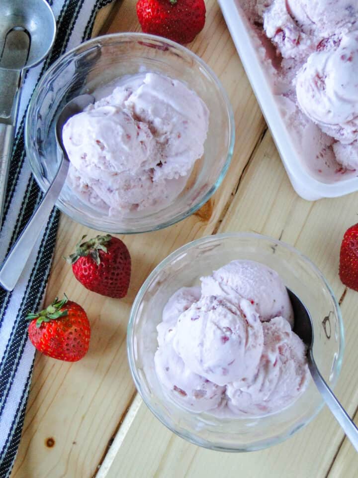 Two sundae bowls with homemade strawberry ice cream and spoons.