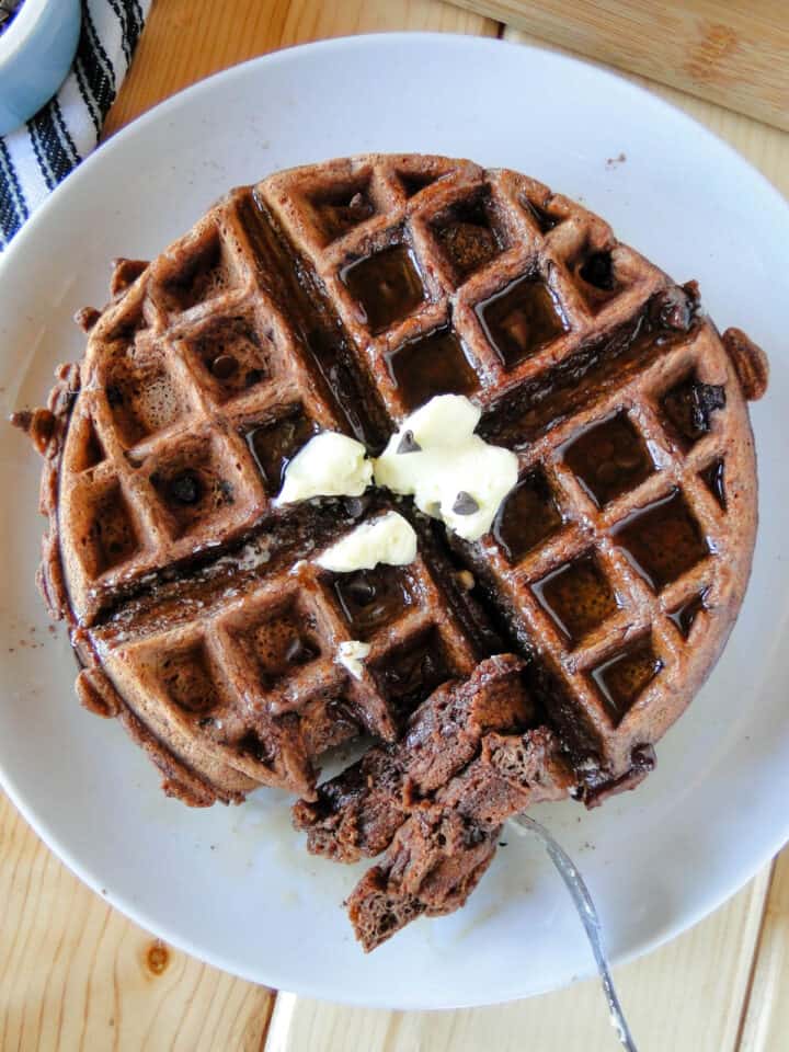 Close up top view of chocolate waffles with bite size piece of fork.