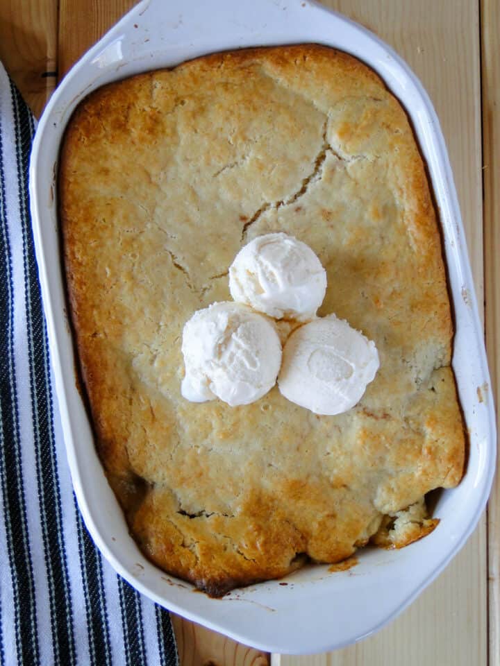 Easy apple cobbler in baking dish with three scoops of ice cream in middle.