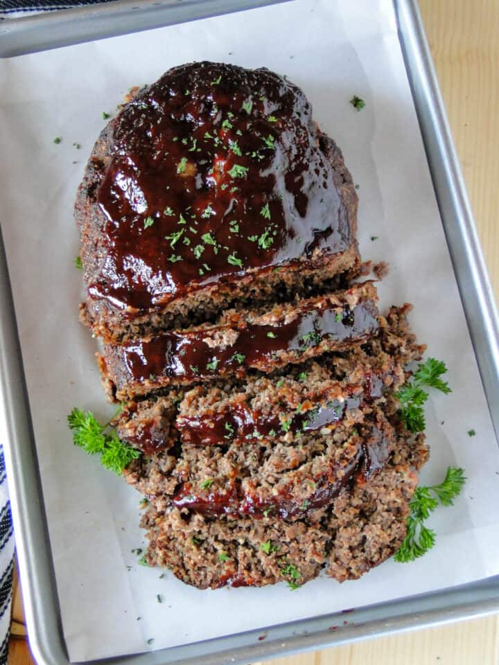 BBQ meatloaf on sheet pan with half of it sliced.