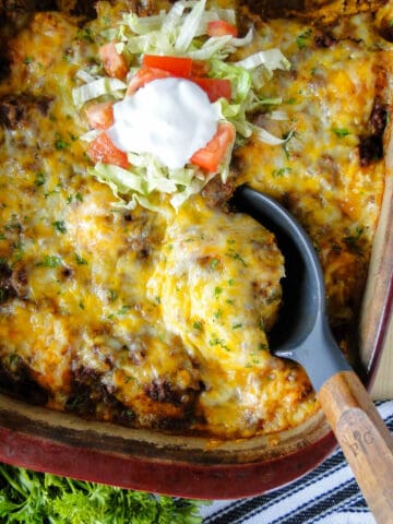 Taco biscuit bake in casserole dish with serving spoon.