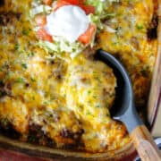 Taco biscuit bake in casserole dish with serving spoon.