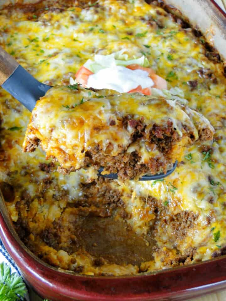 Taco biscuit bake on serving spoon being served from casserole dish.