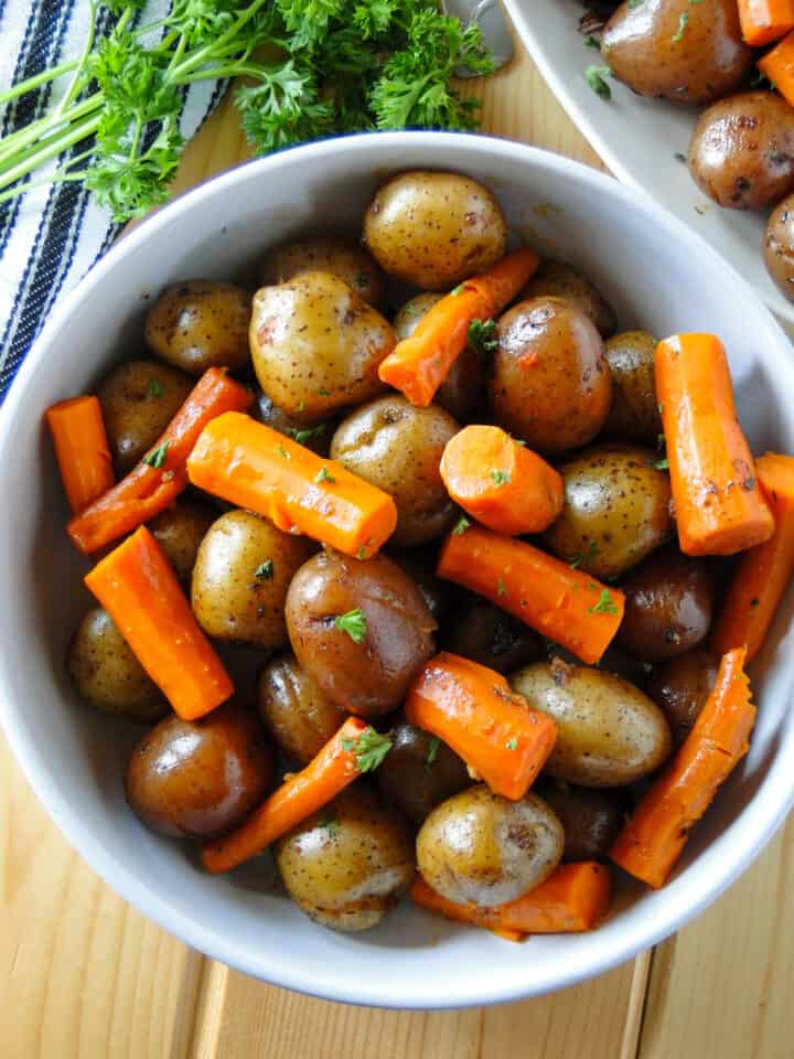 Instant Pot pot roast potatoes and carrots in white round bowl.