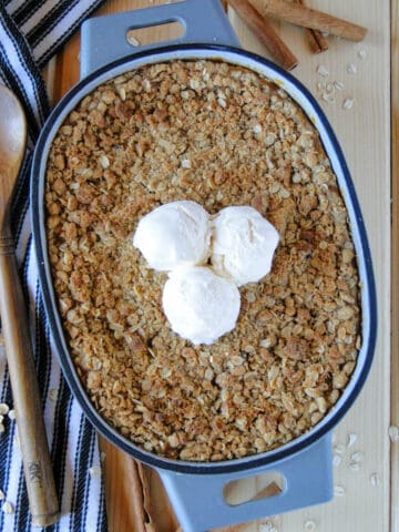 Easy pumpkin crisp in oval baking dish with 3 scoops of ice cream on top.