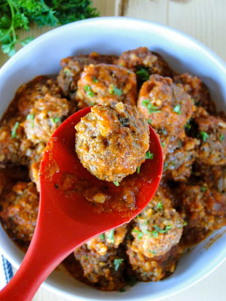 One meatball on spoon on top of Instant pot porcupine meatballs in bowl.