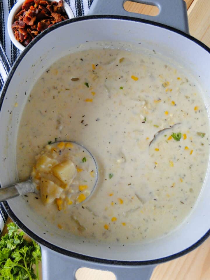 Dutch oven of creamy corn chowder with ladle in it.