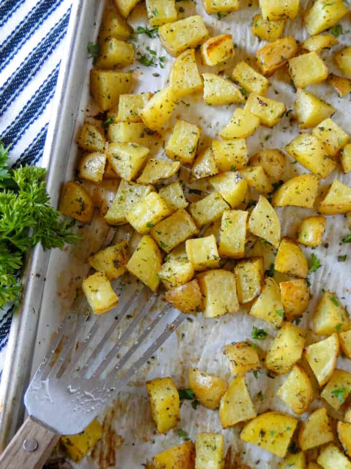 Oven roasted potatoes on sheet pan with spatula.